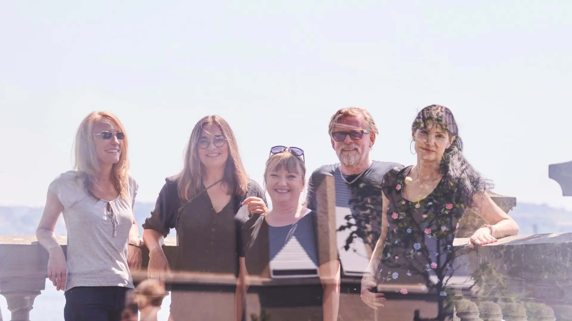 Das Team der GIZZImedia GmbH mit fünf Personen steht am Bodensee an einer Mauer.